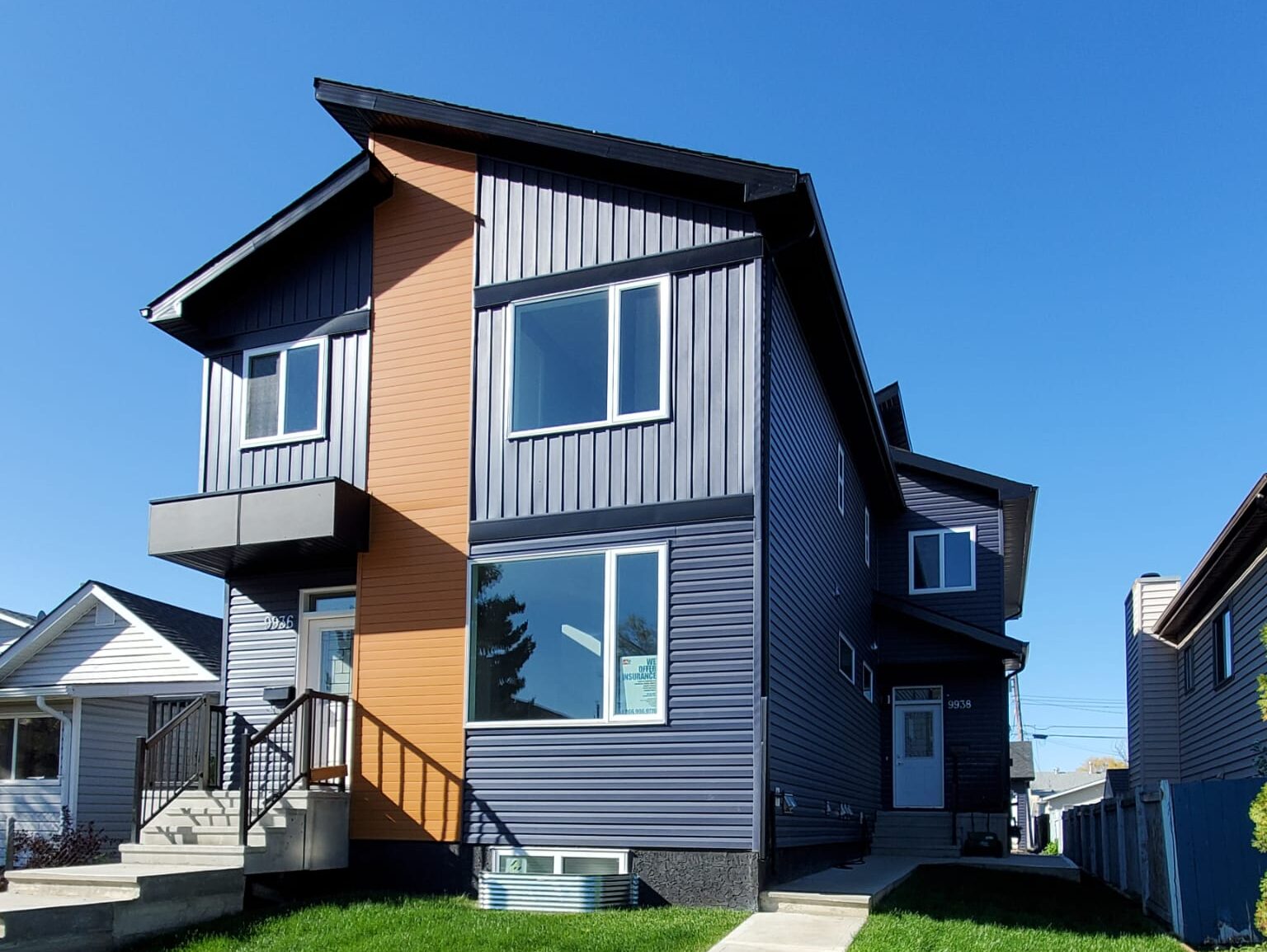 A modern infill home in an Edmonton neighborhood, featuring clean lines, mixed materials (wood, stone, concrete), flat rooflines and large windows.
